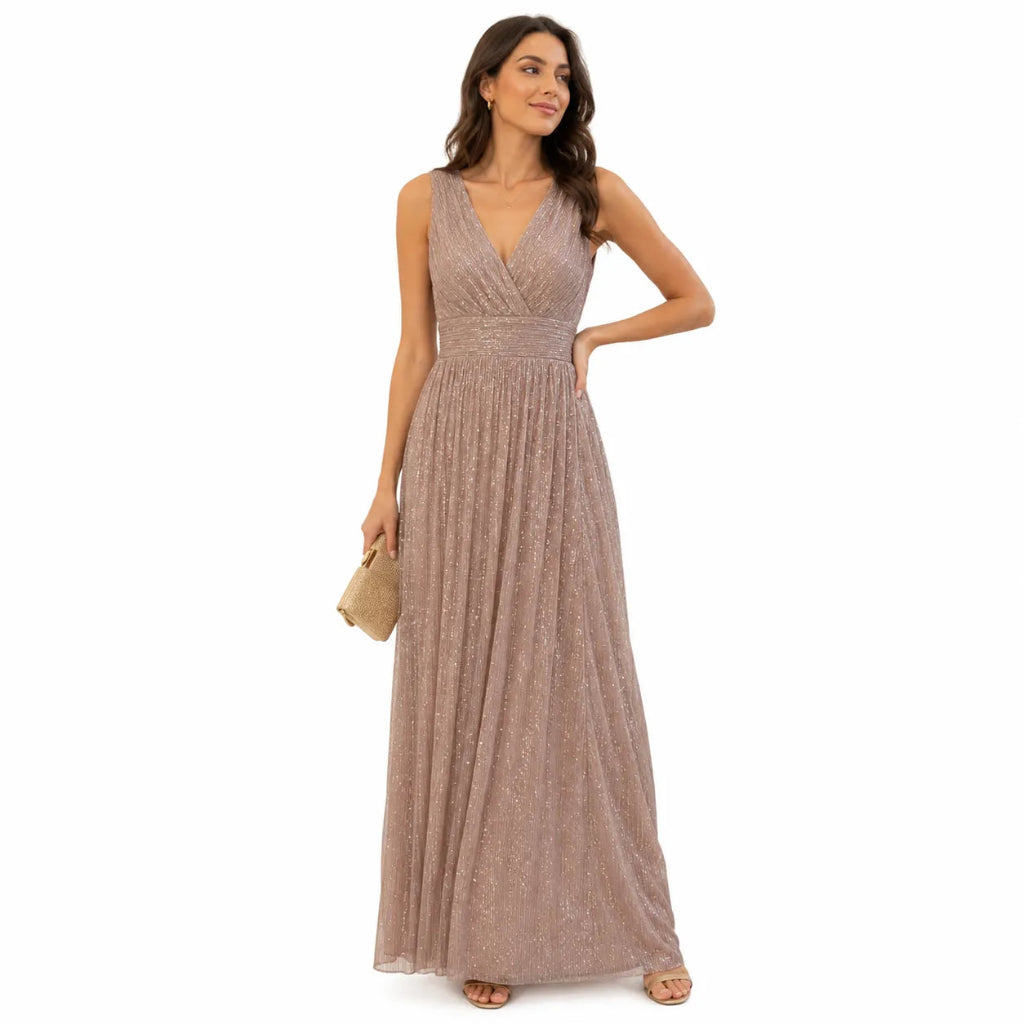 A woman modeling a sleeveless, floor-length mauve-pink sequined gown with a V-neckline and gathered waist, holding a small beige clutch against a plain white background.