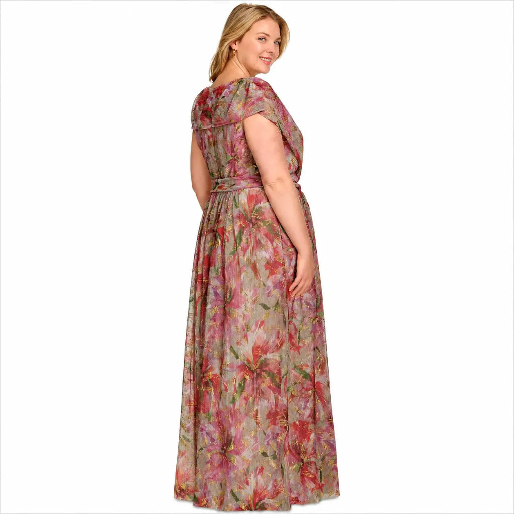 A woman modeling a floor-length floral maxi dress with cap sleeves and a matching waist tie, shown from a three-quarters back angle against a plain white background.