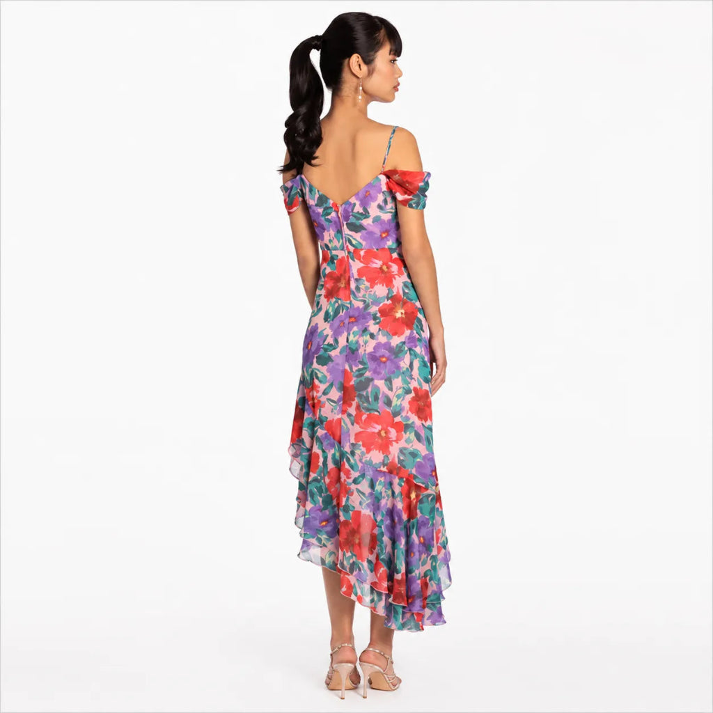 A woman modeling a colorful floral off-the-shoulder midi dress, shown from the back against a plain white studio background.