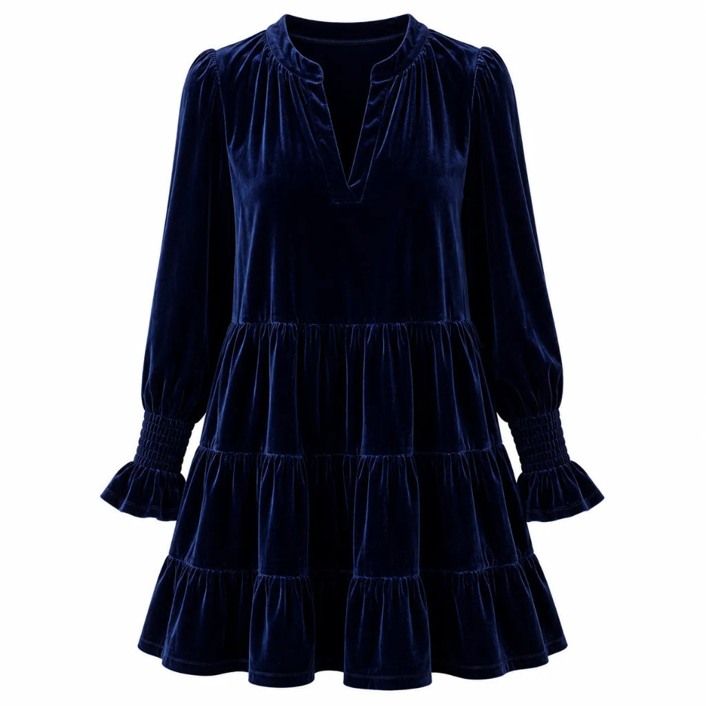 A dark navy blue velvet tiered dress with long sleeves, ruffled cuffs, and a split neckline, shown against a plain white background.