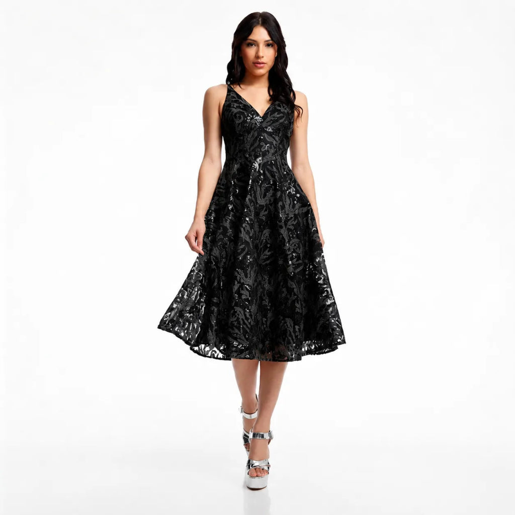 A woman modeling a sleeveless black midi dress with a floral lace pattern, V-neckline, and flared skirt against a plain white studio background.