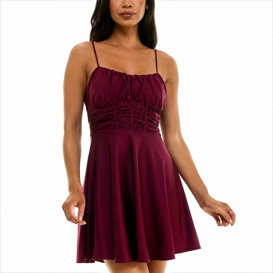 A woman wearing a sleeveless, skater-style mini dress in deep burgundy with a gathered bodice and thin shoulder straps, shown against a plain white background.