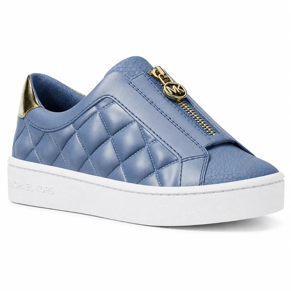 A blue quilted slip-on sneaker by Michael Kors, featuring a gold-tone zip closure with a signature MK logo charm, a gold heel accent, and a thick white platform sole.