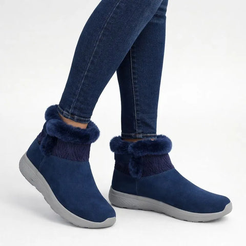 Navy blue ankle boots with fur trim worn with jeans on a white background