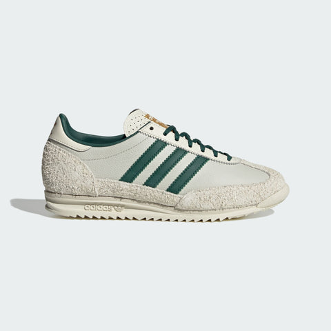 White Adidas sneaker with green stripes on a light gray background