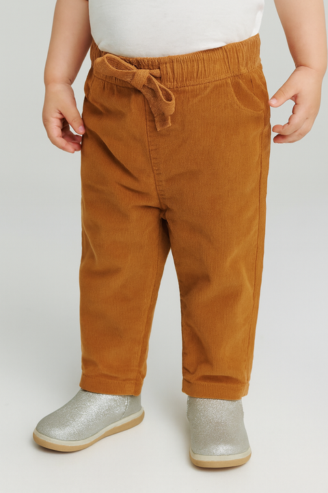 Child wearing brown corduroy pants and silver shoes on a white background