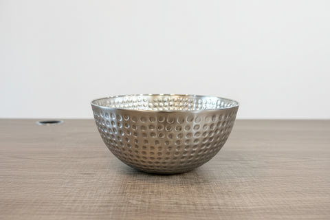 Metallic bowl with textured surface on a wooden surface