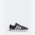 A black Adidas low-top sneaker with white three-stripes, a white midsole, and a small red accent on the outsole, shown from the side against a light gray background.