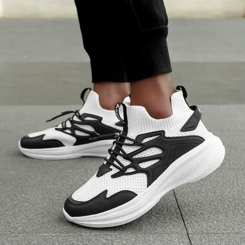 Black and white sneakers worn on a gray pavement