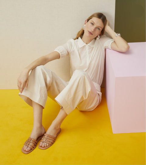 Woman in a white outfit sitting on a colorful geometric surface