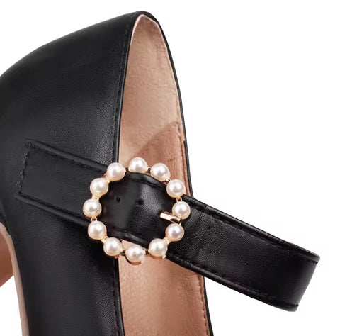 Black high-heeled shoe with a pearl embellished buckle on a white background