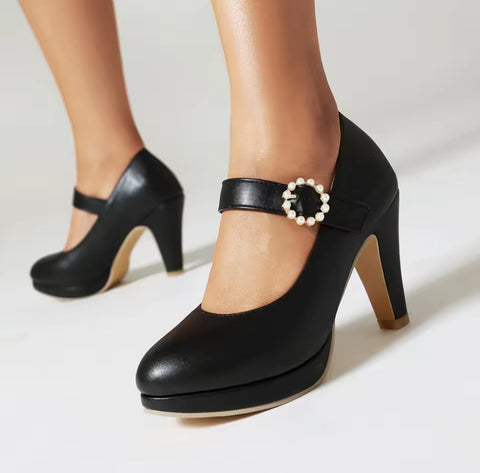 Black high-heeled shoes with pearl embellishments on a white background