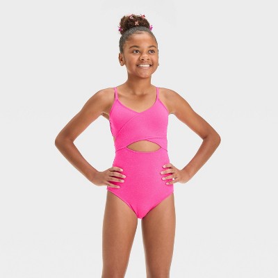 Young girl wearing a pink swimsuit with cut-out design on a white background