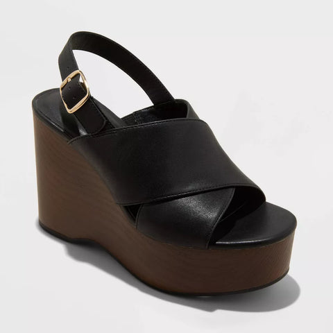 Black wedge sandal with a gold buckle on a light gray background