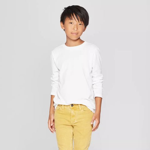 Child wearing a white long-sleeve shirt and yellow pants on a gray background