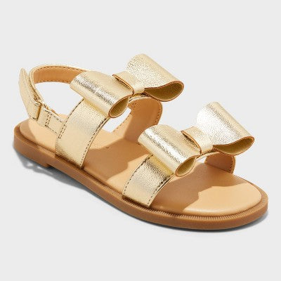 Gold sandal with a bow on a light gray background