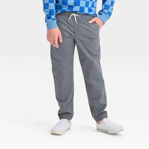 Person wearing gray pants with a blue checkered shirt on a white background