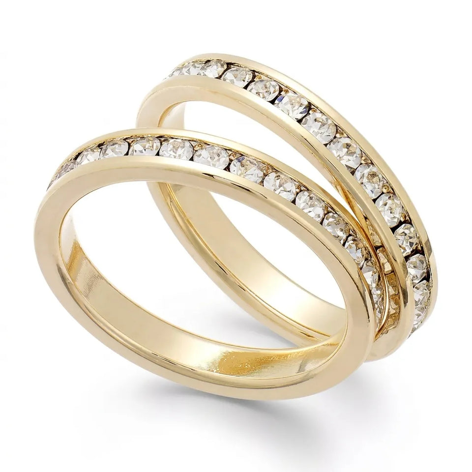 A pair of gold rings with channels set with clear round-cut gemstones, displayed on a clean white background.