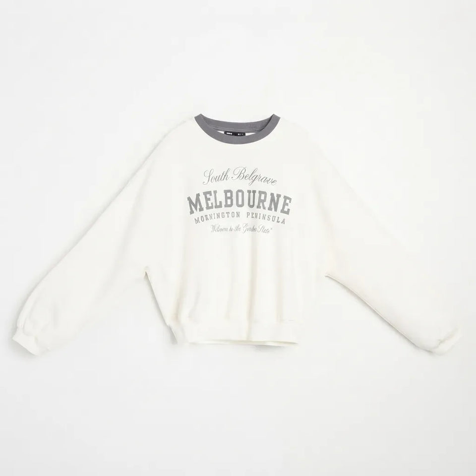 An off-white cropped sweatshirt with a gray ribbed crew neck and gray graphic text on the chest reading 'South Belgrave MELBOURNE WESTMINSTER PENNSYLVANIA'.