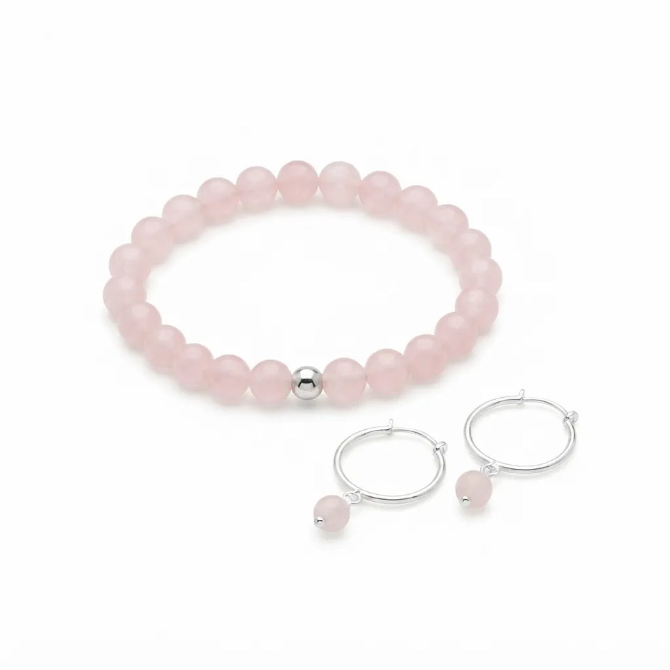 A pink beaded bracelet with a single silver accent bead, displayed alongside a matching pair of silver hoop earrings with small dangling pink beads on a clean white background.