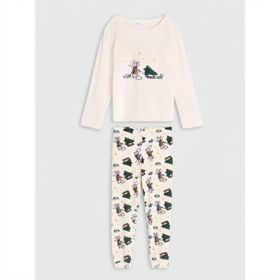 A two-piece children's pajama set consisting of a cream long-sleeve top with a moon and rabbit graphic, and matching cream pants with a dark green and black pattern.