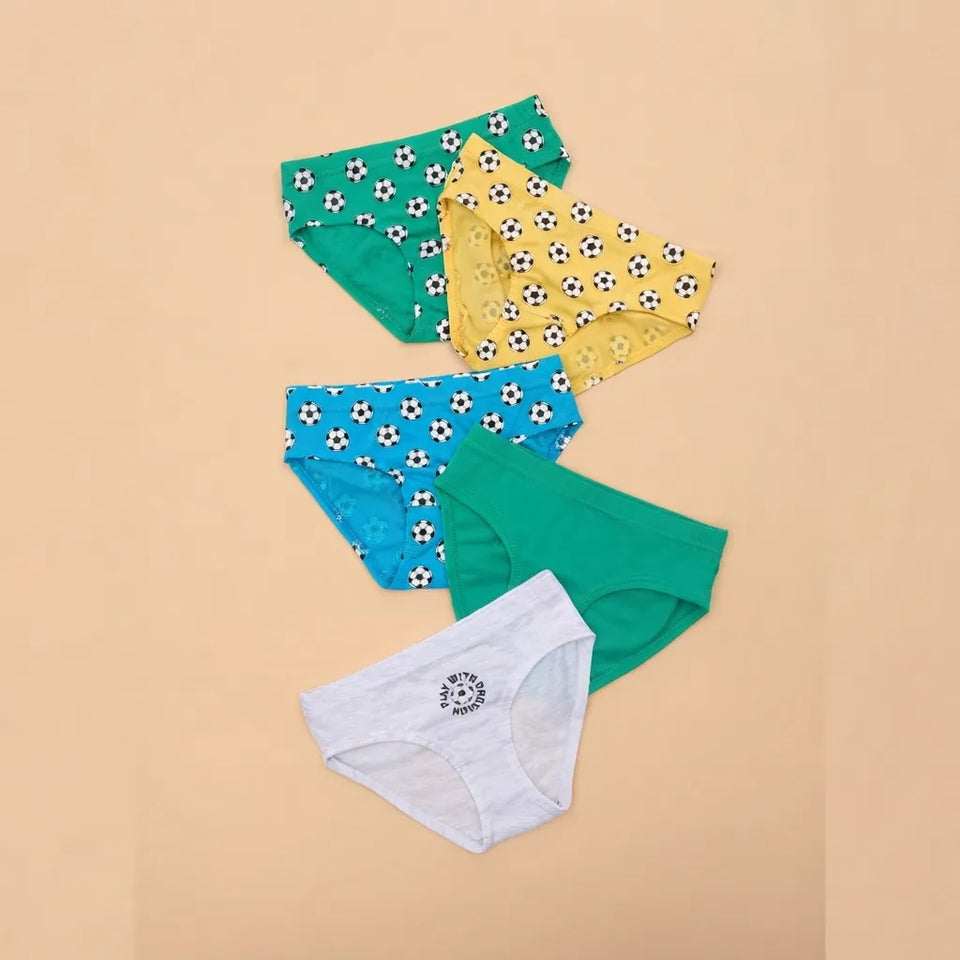 Four pairs of women's briefs arranged on a warm beige background: one green pair with a black-and-white soccer ball pattern, one yellow pair with a floral print, one blue pair with a soccer ball pattern, one solid green pair, and one light gray pair with a small circular logo.