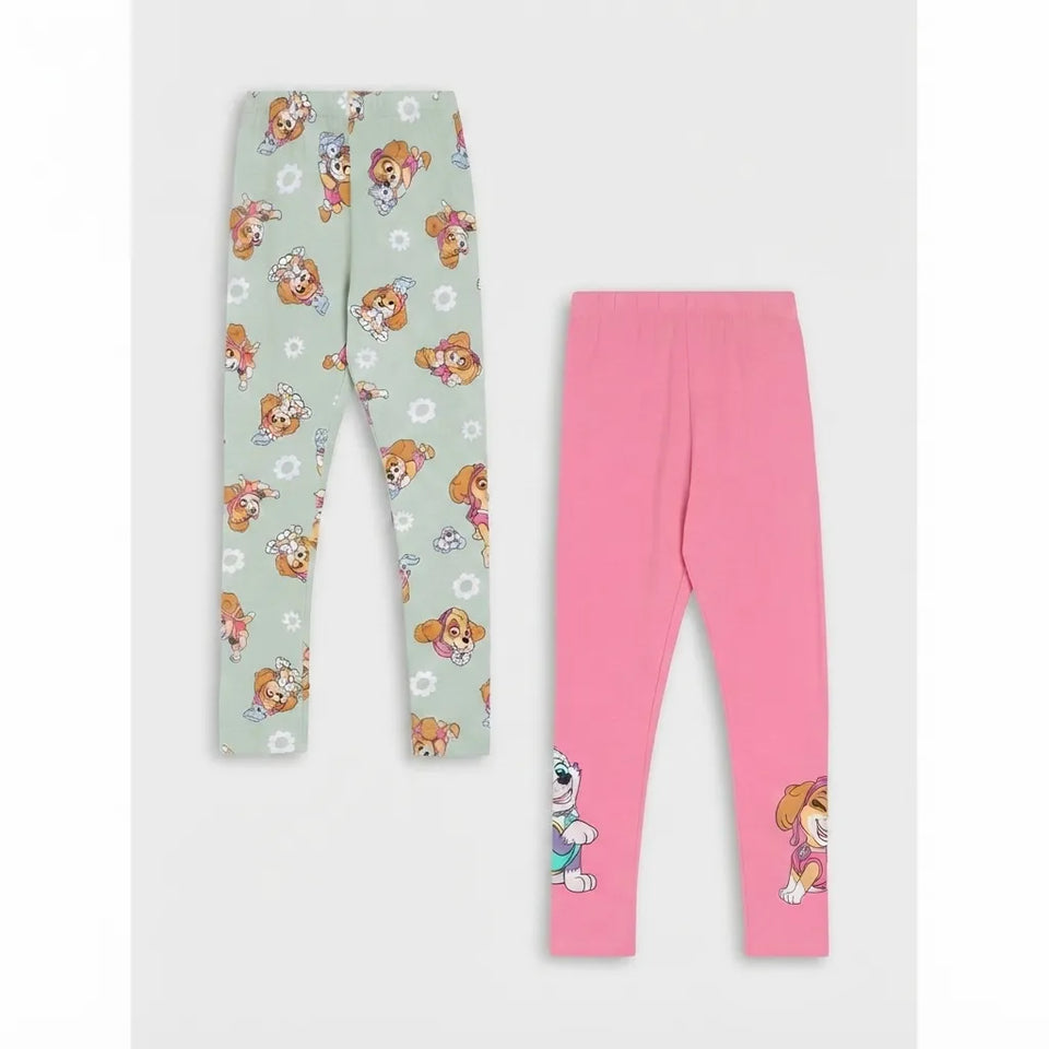 Two pairs of children's leggings laid flat on a light gray background. One pair is pale mint green with an allover cartoon dog print, and the other is bright pink with small cartoon dog graphics near the lower legs.