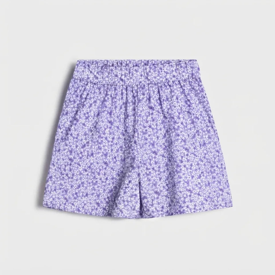 A pair of girls' shorts featuring a purple and white floral print, displayed flat against a light gray background.