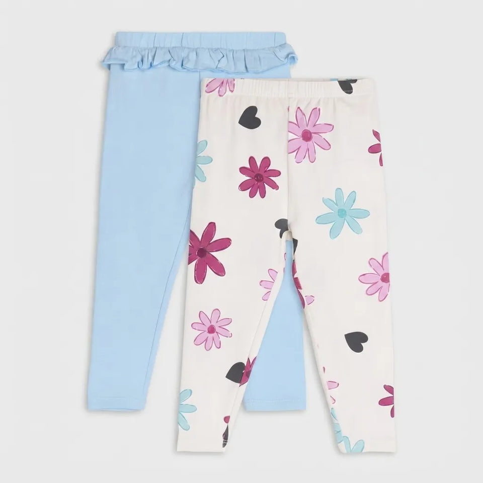 Two pairs of children's leggings laid flat on a light gray background. One pair is solid light blue with a ruffled waistband, and the other pair is off-white with a floral print in pink, light blue, and black.