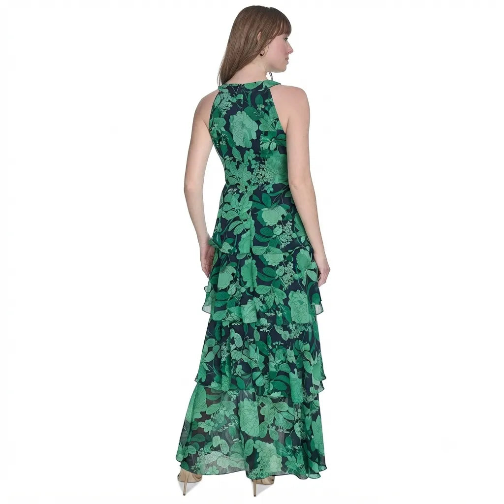A woman modeling a sleeveless, high-neck, floor-length green floral dress from the back, shown against a plain white background.