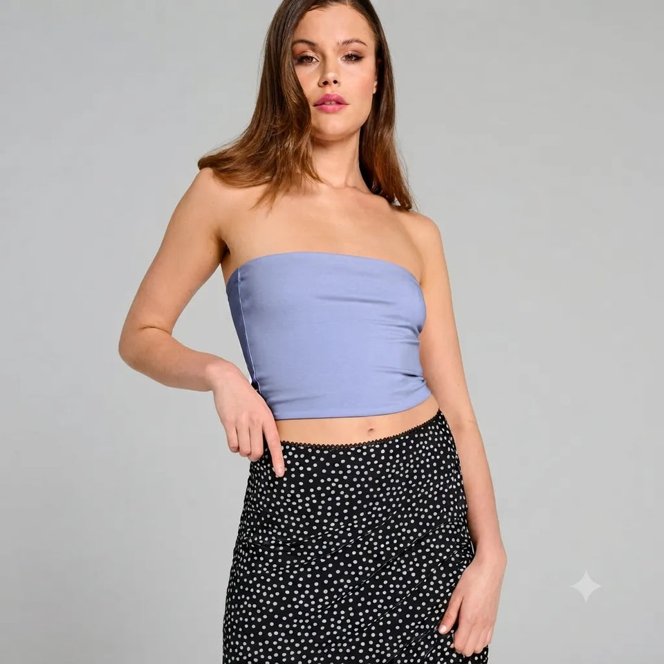 A woman modeling a light blue strapless tube top paired with a black and white polka dot skirt, photographed against a solid light gray studio background.