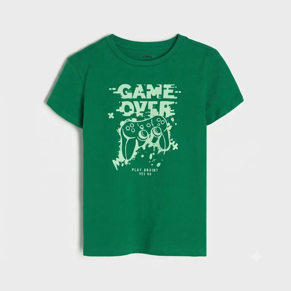 A green short-sleeve t-shirt with a distressed light green graphic on the front featuring the text 'GAME OVER' and a video game controller, displayed on a light gray background.