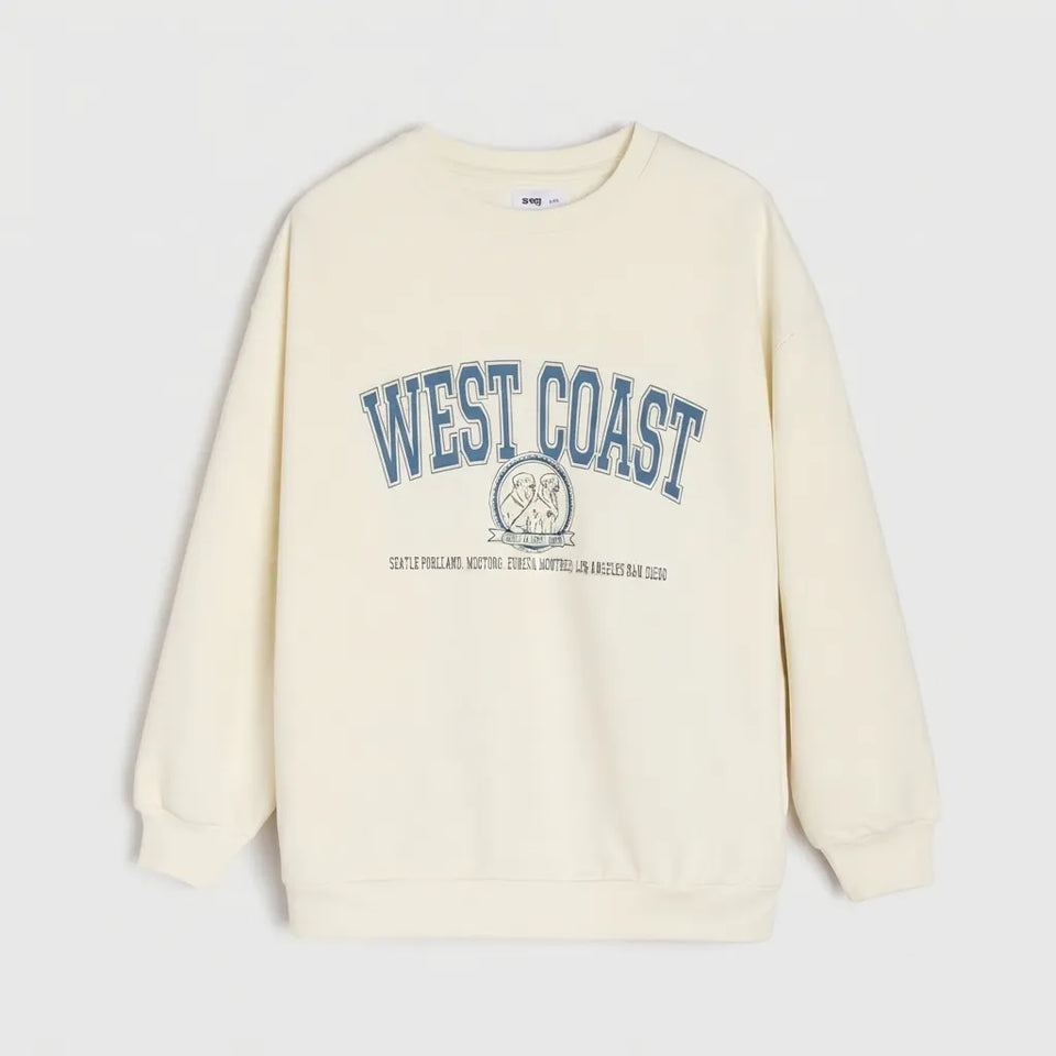 An off-white crewneck sweatshirt featuring a blue 'WEST COAST' graphic with a circular emblem and small text printed on the chest, displayed against a light gray background.