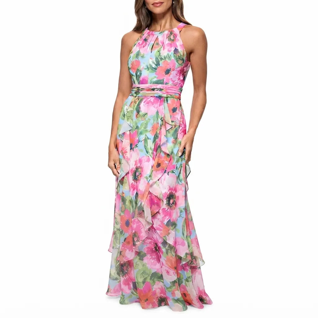 A sleeveless halter-neck maxi dress with a vibrant pink, green, and orange floral print, featuring a matching waist tie, shown on a model against a white background.