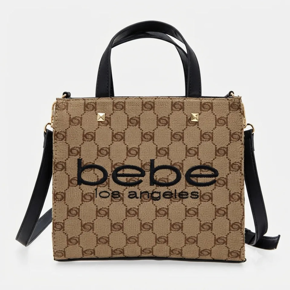 A structured tote bag with a beige and brown monogram pattern, black leather handles and shoulder strap, and gold-tone hardware. The front features the text 'bebe los angeles' in black.