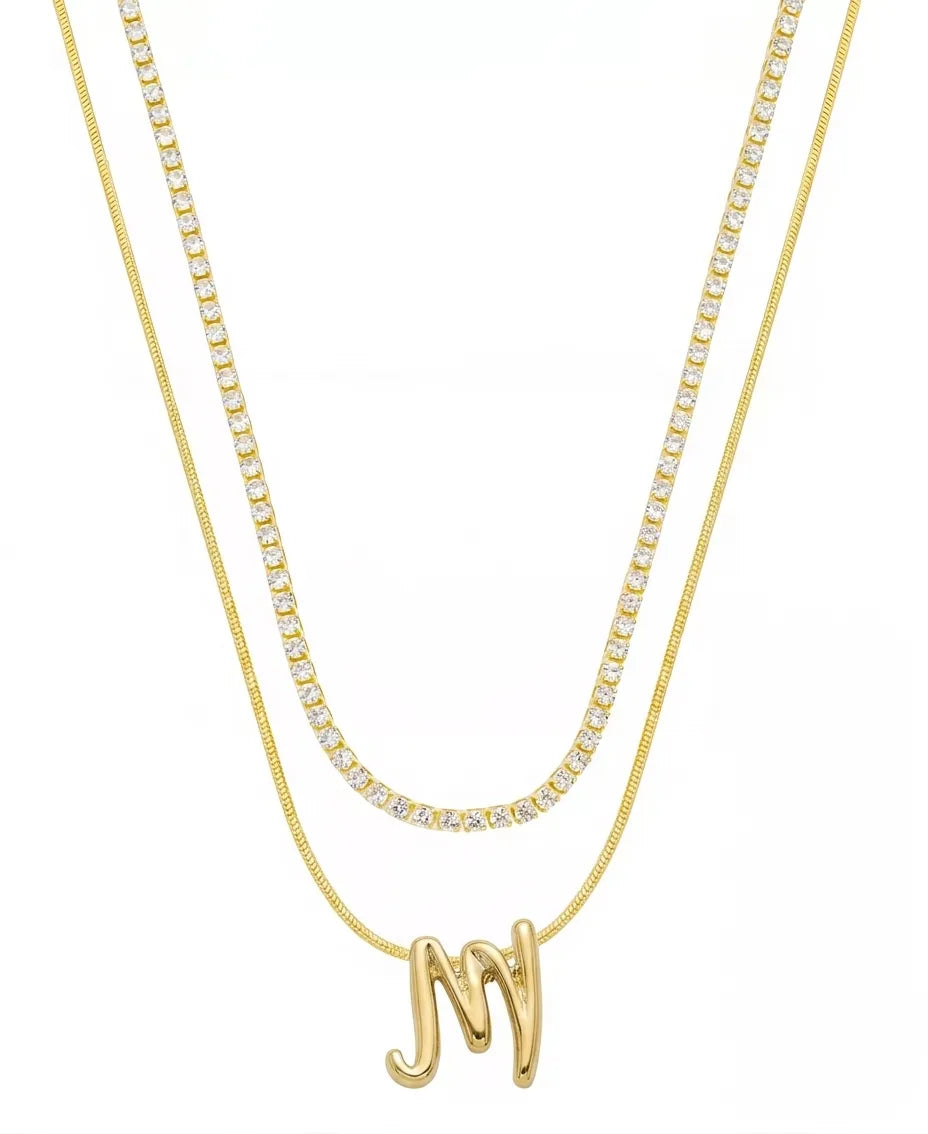 Two gold necklaces on a white background: a longer chain necklace and a shorter chain necklace with a script letter 'M' pendant.