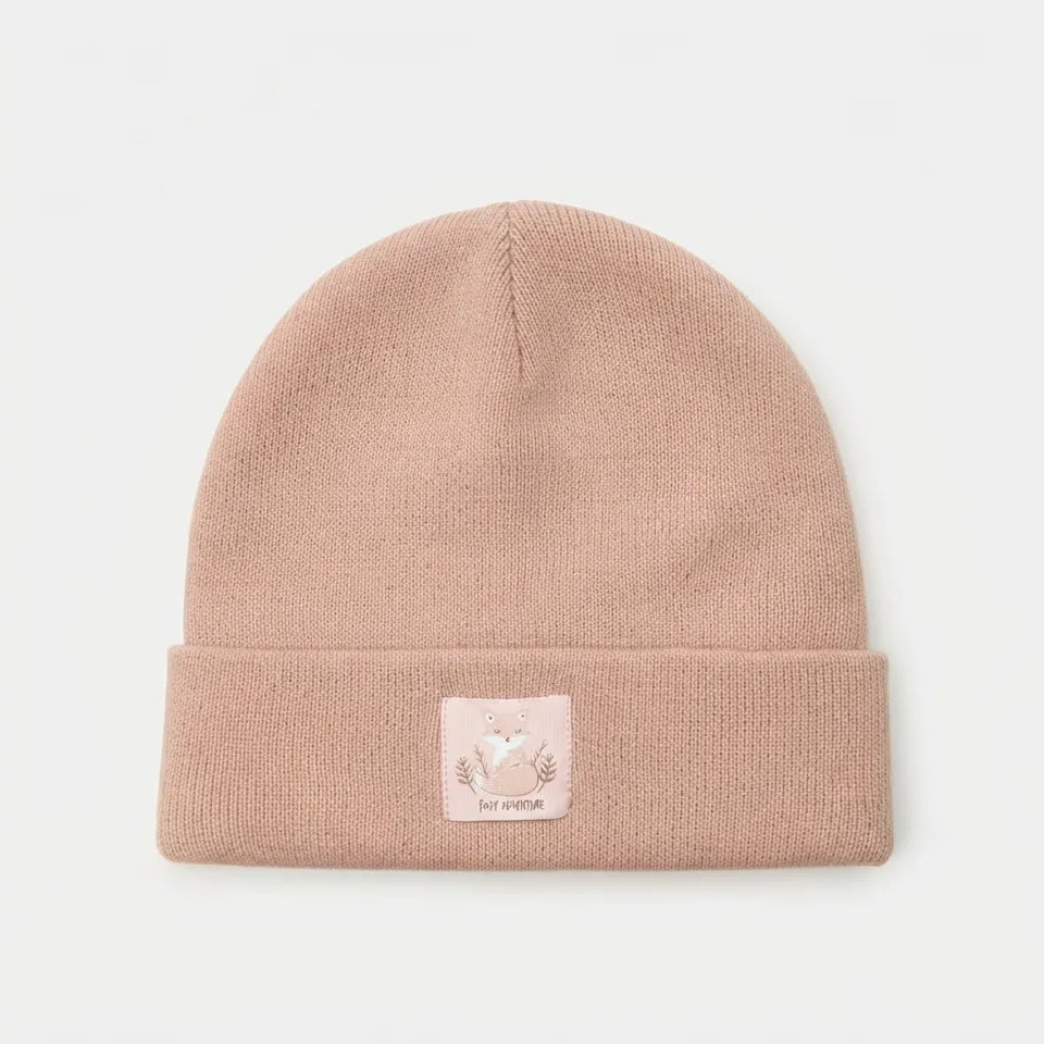 A dusty pink knit beanie hat with a folded cuff and a small square patch featuring a fox illustration and the text 'MY PUPPIE'.