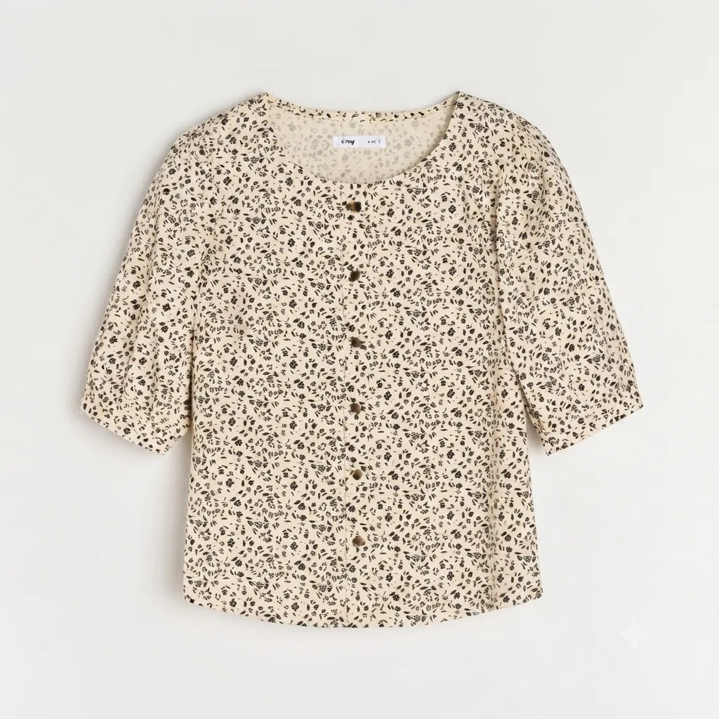 A short-sleeve button-up blouse with a beige and brown leopard print pattern, laid flat against a light off-white background.