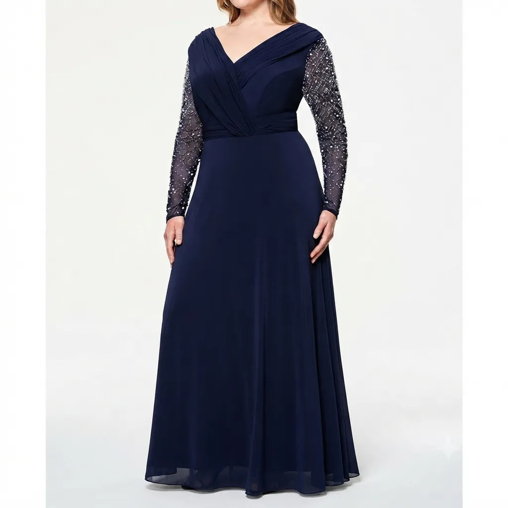 A navy blue floor-length gown with a V-neckline, draped bodice, long sheer beaded sleeves, and a flowing skirt, shown on a model against a light gray studio background.