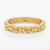 A polished yellow gold bangle bracelet with a textured, ribbed design, displayed on a clean white background.