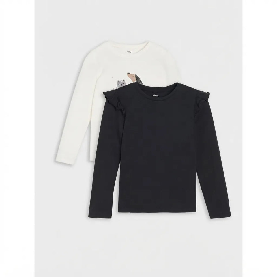 Two long-sleeve children's tops layered on a light gray background: a black top in front with ruffled shoulder details, and a white top behind with a small cat graphic on the chest.
