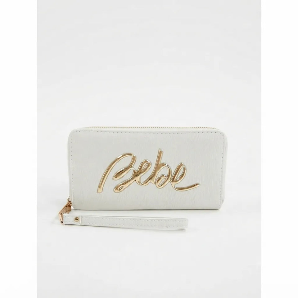 A white faux leather zip-around wallet with a wristlet strap, featuring a prominent gold metallic 'Bebe' script logo on the front, set against a plain white background.