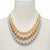 A multi-strand pearl necklace displayed on a cream-colored mannequin bust. The necklace features three strands: one strand of cream pearls, one strand of champagne-gold pearls, and one strand of silver-gray pearls, accented by silver-toned links with small clear crystals.