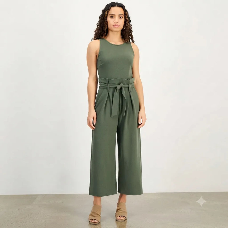 A woman modeling a sleeveless olive green jumpsuit with a matching waist tie, photographed against a plain light gray studio background.