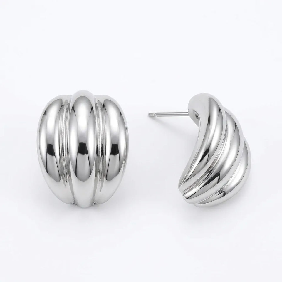A pair of polished silver-tone stud earrings with a ribbed, rounded design, shown on a clean white background with one earring facing forward and the other showing the side profile and post.