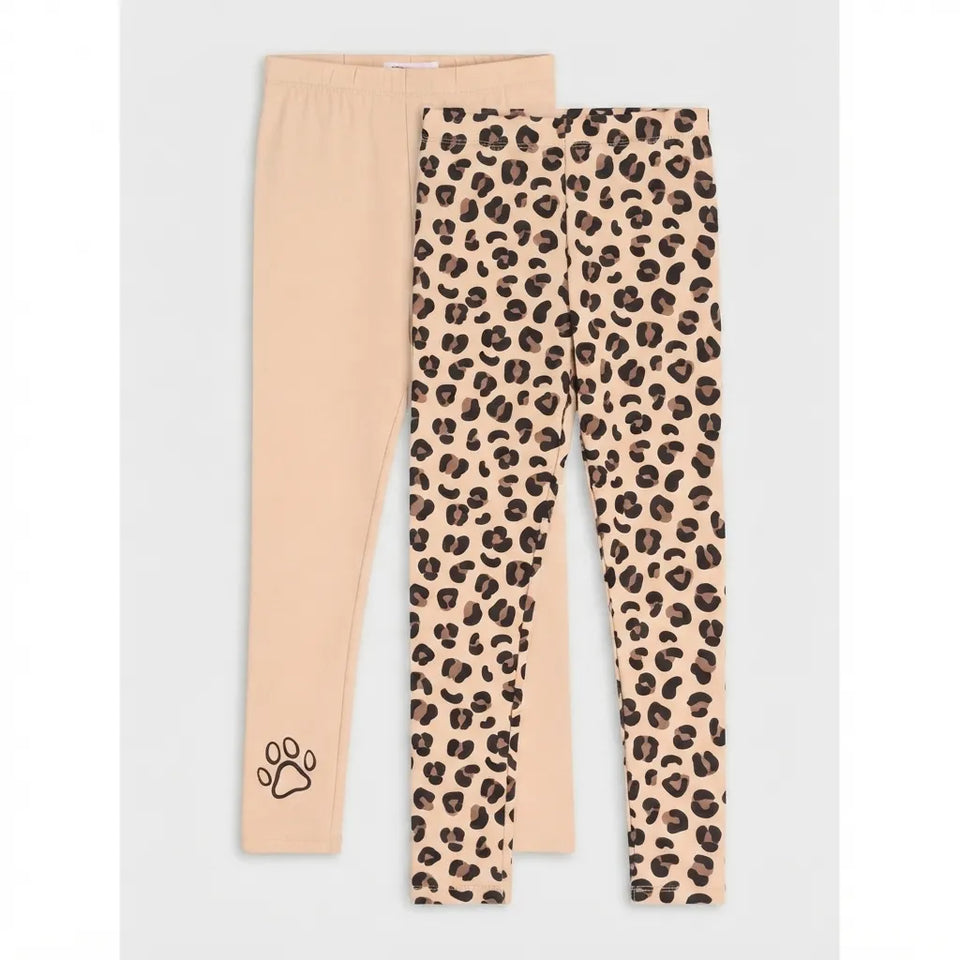 Two pairs of children's leggings laid flat on a light gray background. The front pair has a beige and brown leopard print pattern, and the back pair is solid light beige with a small black paw print near the hem.