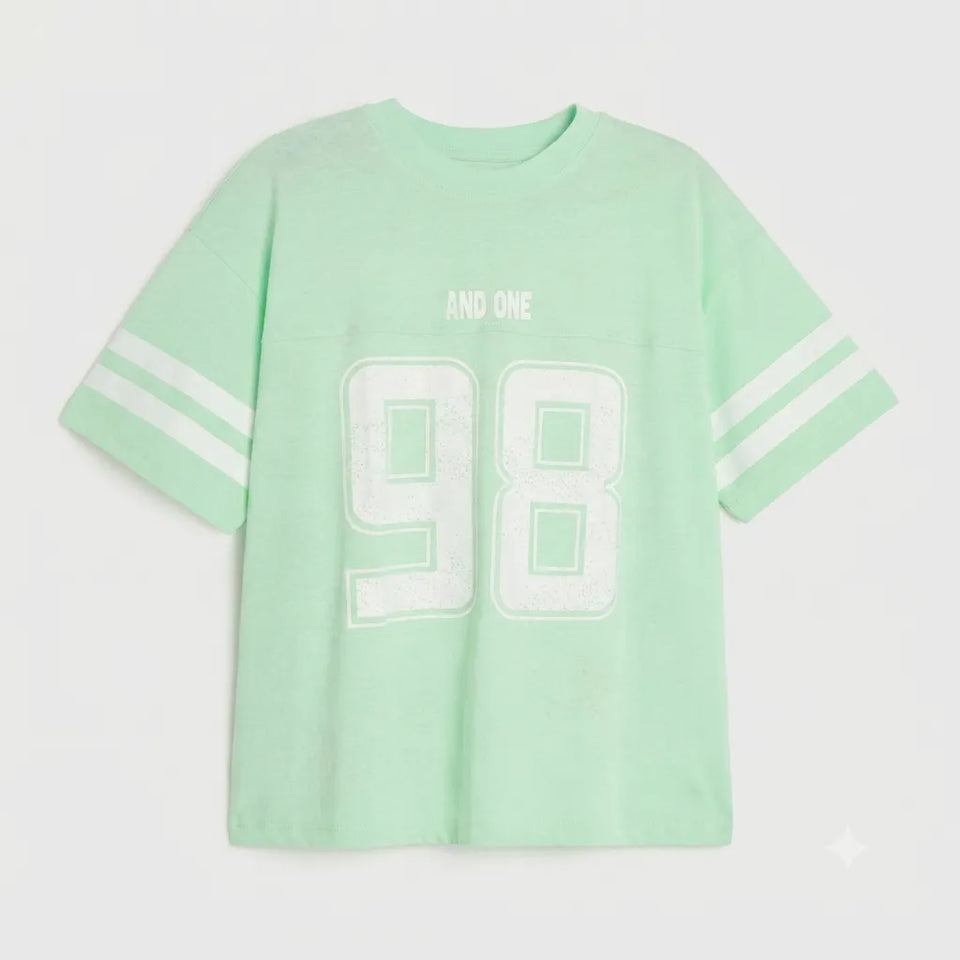 A mint green short-sleeve t-shirt with white stripes on the sleeves and a large white distressed '98' graphic on the front, with 'AND ONE' printed above it.
