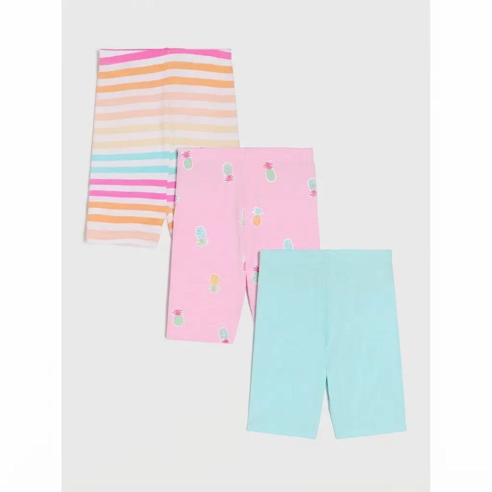 Three pairs of children's leggings laid flat on a light gray background: one pair with pastel horizontal stripes in pink, orange, yellow, and blue; one pair in light pink with small multicolor fruit prints; and one pair in light aqua blue.