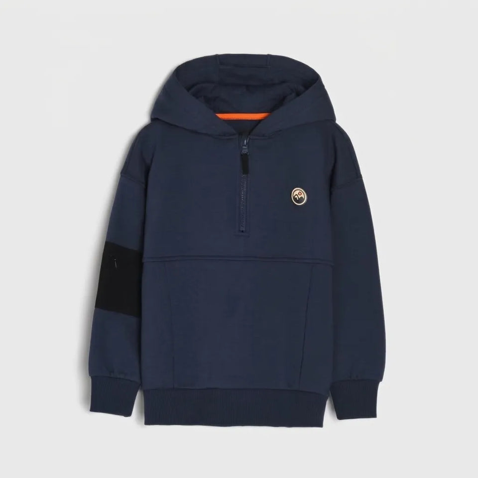 A navy blue quarter-zip hoodie with a black color-blocked sleeve panel, a small circular embroidered logo on the left chest, and an orange inner hood lining, shown against a light gray background.