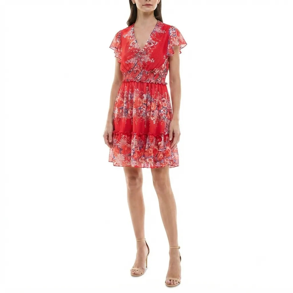 A woman modeling a red tiered mini dress with a floral print, ruffled short sleeves, and a V-neckline, paired with beige high-heeled sandals against a plain white background.